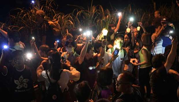 Pro-democracy demonstrators use the torch lights of their phones and hold lanterns while forming a human chain on Victoria Peak in Hong Kong