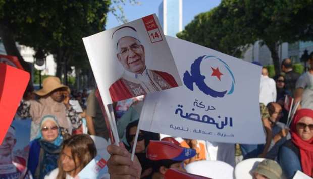Supporters of Ennahdha's Tunisian presidential candidate Abdelfattah Mourou (portrait) attend a campaign event along Habib Bourguiba avenue in the centre of the capital Tunis