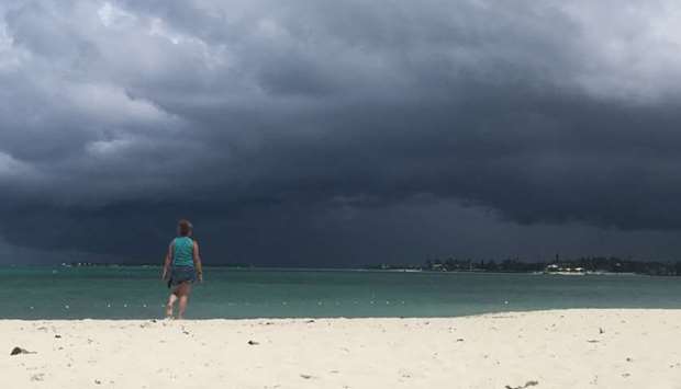 A woman walks on the beach as a storm approaches in Nassau, Bahamas yesterday.