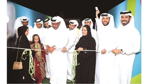 Director General of the organising Committee Dahlan al-Hamad cuts a ribbon to open the u2018Volunteers Entertainment Tentu2019 at Aspire Zone yesterday. Picture on right shows volunteers posing with officials and representatives of various departments.