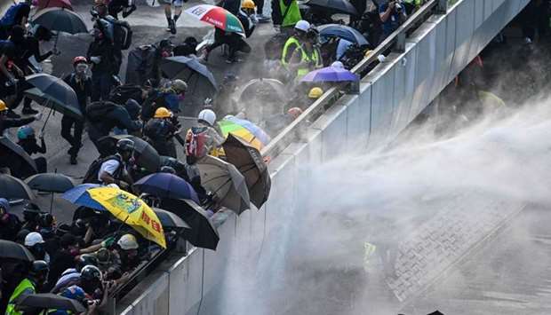 Pro-democracy protesters react as police fire water cannons outside the government headquarters in Hong Kong