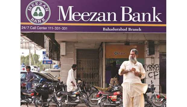 Pedestrians pass in front of a branch of Pakistanu2019s biggest Islamic lender Meezan Bank in Karachi. Market share of Islamic banking assets in the overall banking industry in Pakistan by the end of last fiscal year rose to 14.4% compared to 12.9% in June 2018, said the State Banku2019s Islamic Banking Bulletin: April-June 2019 on Friday.