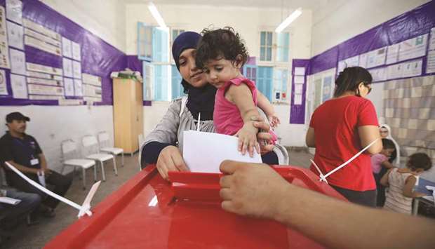 A woman carries a child as she casts her vote at a polling station during the presidential election in Tunis, yesterday.