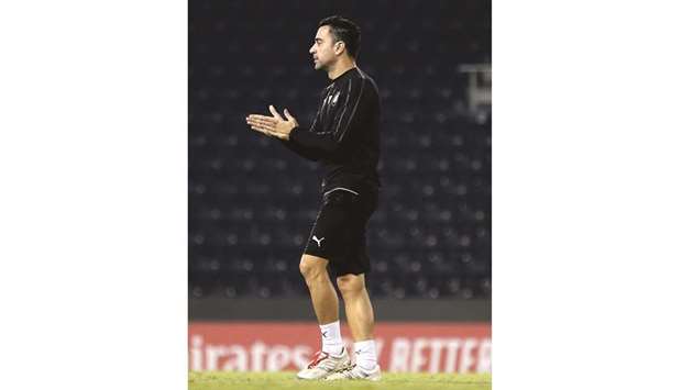 Al Sadd coach Xavi watches his team (below) during a training session yesterday.