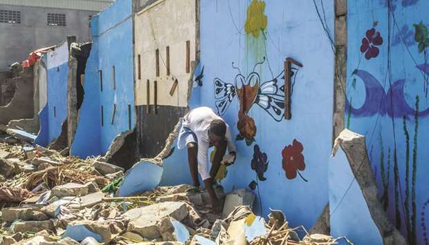 A boy sifts through the rubble for objects from his house after its demolition in Xwlacodji, in the 5th arrondissement of Cotonou on September 3.