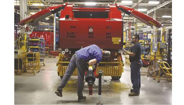 Workers review an assembled New Holland round baler at the companyu2019s factory in Pennsylvania. US manufacturing output increased solidly in August, boosted by a surge in the production of machinery and other goods, but the outlook for factories remains weak amid rising headwinds from trade tensions and slowing global economies.