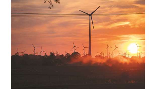 Wind turbines stand as the sun sets during wheat harvest in Wustermark, Germany (file). Global green-bond sales have already beaten last yearu2019s record $135bn well before the end of 2019. Issuance of the securities has more than quadrupled in the past five years, according to data compiled by Bloomberg.