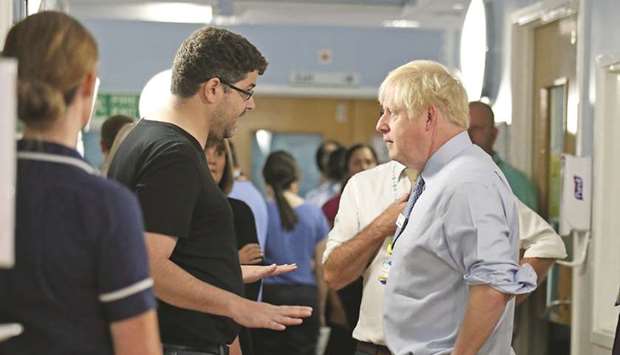 Prime Minister Boris Johnson speaks with the father of a young girl, who is being treated in the Acorn Childrenu2019su2019 Ward, during a visit to Whipps Cross University Hospital in Leytonstone, London,