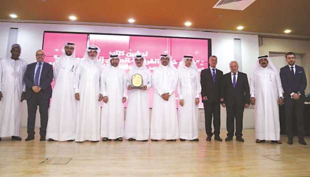 HE the Minister of State Dr Hamad bin Abdulaziz al-Kuwari holding the shield poses for a photo with other dignitaries.