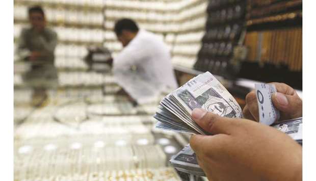 A man counts Saudi riyal banknotes in a jewellery store in Riyadh (file). The Saudi Arabian Monetary Authority has cut its repo rate by 25 basis points to 2.5% and its reverse repo rate to 2%.