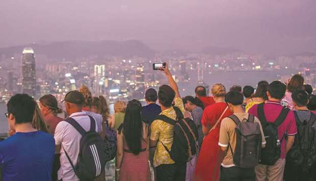 Tourists look at the cityu2019s skyline from a viewing terrace on Victoria Peak at dusk in Hong Kong. Despite slowing growth in China thatu2019s roiling markets, the worldu2019s No 2 economy is still adding the size of the Australian economy every year, according to McKinsey analysts.