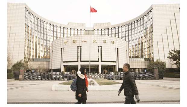 Pedestrians walk past the Peopleu2019s Bank of China headquarters in Beijing. China cut its new one-year benchmark lending rate for the second month in a row yesterday, a step by the PBoC to try to wrestle down borrowing costs and support the economy as the Sino-US trade war drags on.