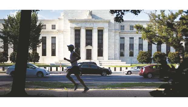 A runner passes the Federal Reserve building in Washington, DC. The central bankers may often be called on to speak with one voice, but the Fed now has three u2014 those ready to reduce rates even lower to ward off economic risks, those ready to stand pat and watch the data for now, and those warning that the Fed may already be fuelling a credit bubble.