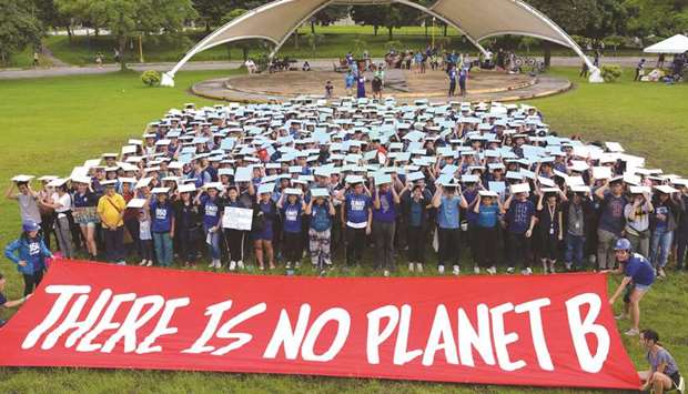 Activists comprised of students and professionals gather in front of a banner as they take part in a world-wide climate rally, at the University of the Philippinesu2019 campus in Manila, yesterday.