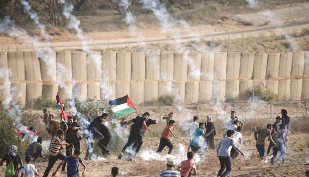 Palestinian protesters run for cover from tear gas fired by Israeli forces during clashes  following a demonstration along the border east of Bureij in the central Gaza Strip, yesterday.