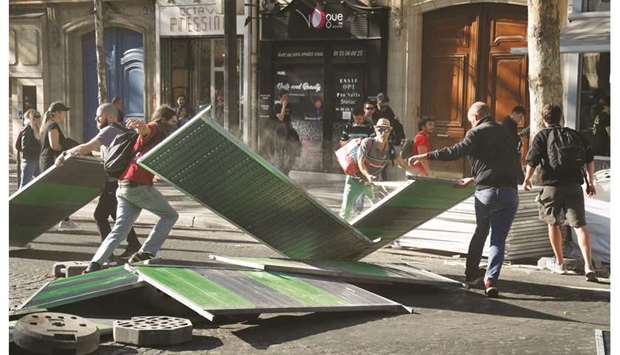Protesters use metallic barriers to set a barricade in Paris yesterday during an anti-government demonstration called by the u2018yellow vestu2019 (gilets jaunes) movement.