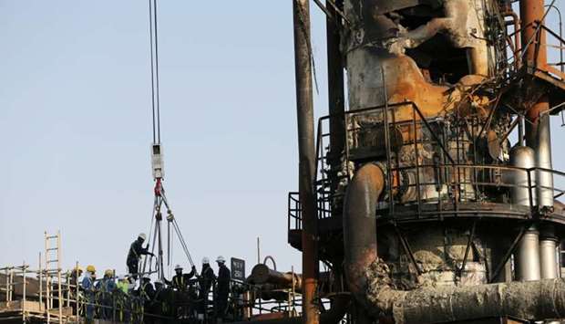 Workers are seen at the damaged site of Saudi Aramco oil facility in Abqaiq, Saudi Arabia, Saturday