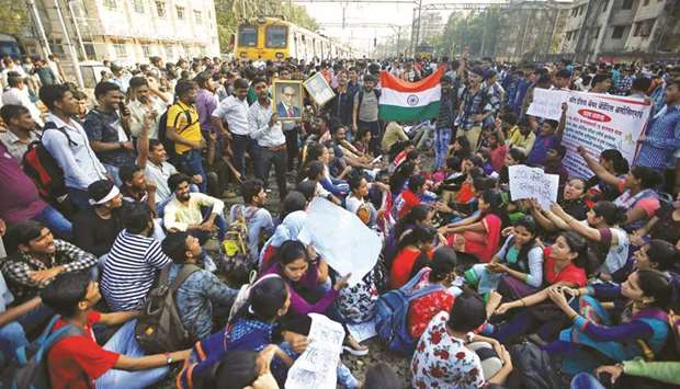 People sit on railway tracks as they block train services during a protest demanding recruitment into the railway services in Mumbai, on March 20, 2018. An annual report by the Swiss bank UBS looking at the number of hours worked in different cities found Mumbai, Indiau2019s largest city, to be the worldu2019s hardest-working city, clocking up the longest average working hours of 3,315 per year per worker.