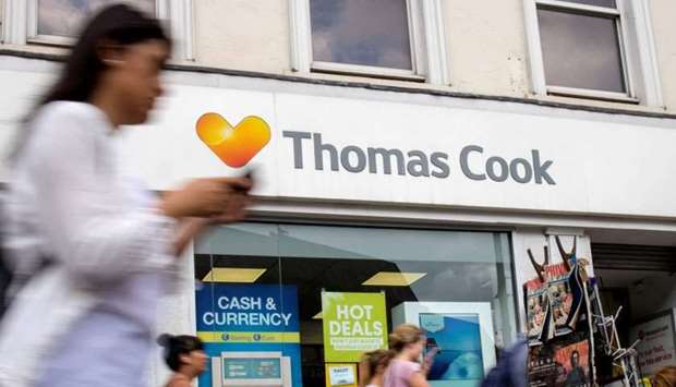 Pedestrians are pictured walking past a branch of a Thomas Cook travel agent's shop