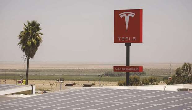 A signage is displayed above a solar canopy at a Tesla Supercharger station in Kettleman City, California (file). By 2050, BNEF expects renewables to account for 48% of the US power system.