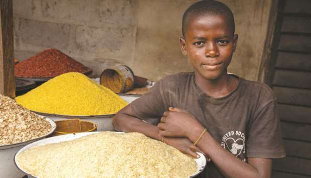 A boy sits next to grain bins in his shop at Ajara Market in Badagry, near Lagos.