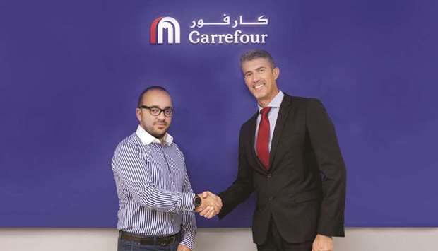 Talabat and Carrefour Qatar officials shake hands at the start of their partnership.