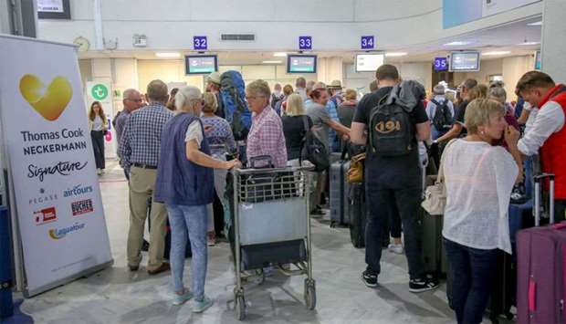 People line up in front of a counter of Thomas Cook at the Heraklion airport on the island of Crete,