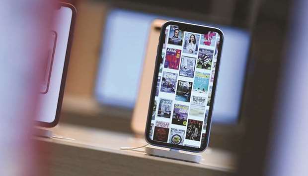 Front pages of newspapers and magazines are displayed on an iPhone during the grand opening and media preview of the new Apple Carnegie Library store in Washington on May 9, 2019 (file photo). Newspapers have succumbed to the pressures of falling revenues caused by a shift in reading habits and by the migration of advertising revenues to principally Google and Facebook.