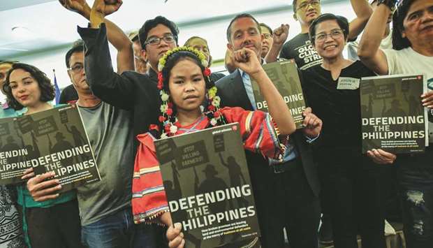 Campaigner Ben Leather (third right, front) from international rights watchdog Global Witness, along with indigenous peoples, campaigners and their supporters, holds up a newly released human rights report during a press conference in Manila, yesterday.