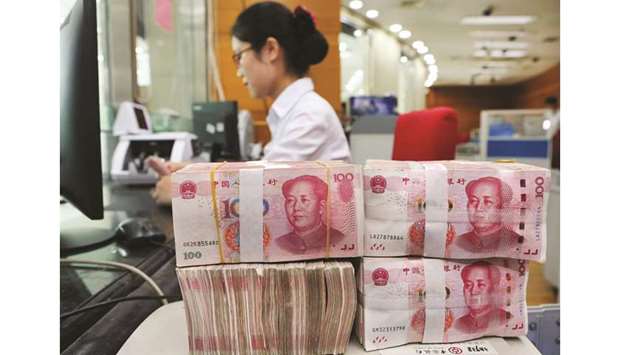 An employee counts 100-yuan notes at a bank in Nantong in Chinau2019s eastern Jiangsu province. China, having let the yuan cross the once sacred red line of 7 per dollar, will allow its currency to fall further and may even risk US anger by using it as a bargaining chip in already thorny trade talks, market participants believe.