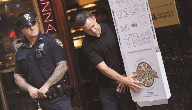 A man hangs a sign written on a pizza box in support of Donald Trump at a restaurant in New York, yesterday, as the US president attends a nearby Republican fundraiser.