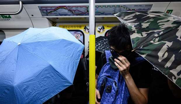 Protesters hold open umbrellas inside an MTR train during a disruption protest in Hong Kong
