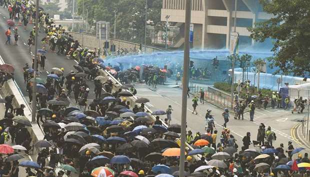 Hong Kong police fire water cannon toward protesters gathered outside the central government offices after taking part in an unsanctioned march through Hong Kong yesterday.