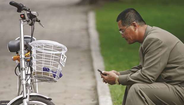 A man uses his mobile phone next to an electric bicycle in downtown Pyongyang, North Korea.