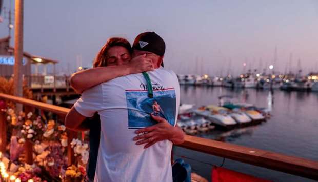 JJ Lambert and Jenna Marsala hug after hanging a scuba flag at a makeshift memorial near Truth Aquatics as the search continues for those missing in a pre-dawn fire that sank a commercial diving boat off a Southern California island near Santa Barbara, California