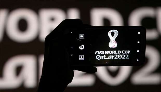 A man takes a picture of the tournament\'s official logo for the Qatar 2022 World Cup