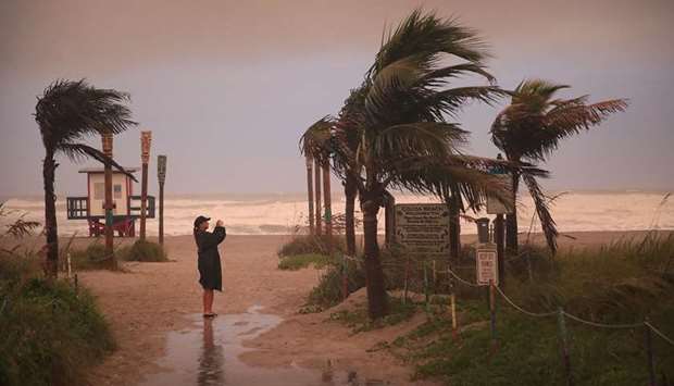 A woman takes a picture as the effects of Hurricane Dorian make an impact on Cocoa Beach, Florida.