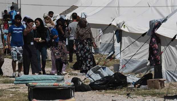 Migrants walk by tents after arriving at Nea Kavala refugee camp, near the city of Kilkis, northern Greece.
