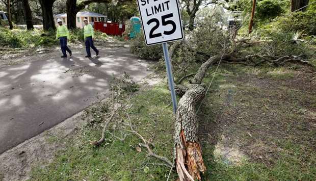 Utility workers walk past a power line brought down by a tree branch after Hurricane Dorian swept through, in Southport, North Carolina