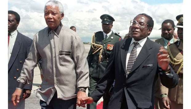 President Robert Mugabe of Zimbabwe (R) holds hands with his South African counterpart Nelson Mandela greeting him on his arrival in the country December 13, 1998.
