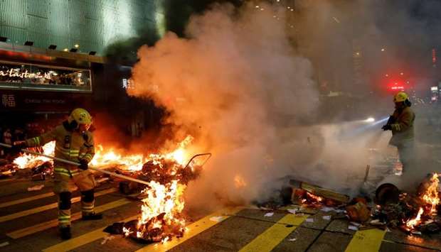 Firefighters try to extinguish a burning barricade during a demonstration in Mong Kok district in Hong Kong