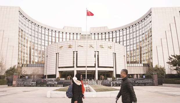 Pedestrians walk past the Peopleu2019s Bank of China headquarters in Beijing. The PBoC said it would cut the reserve requirement ratio by 50 basis points for all banks, with an additional 100 bps cut for qualified city commercial banks. The RRR for large banks will be lowered to 13%.