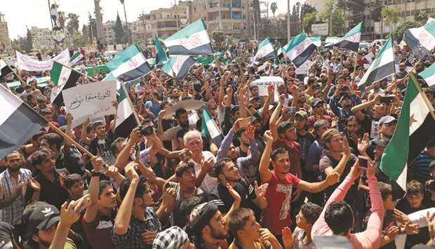 Men chant slogans and wave flags of the Syrian opposition during a demonstration against the government offensive in the northwestern Idlib province, yesterday.