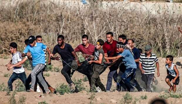 Palestinian protesters carry away a man injured during clashes following a demonstration along the border with Israel east of Bureij in the central Gaza Strip yesterday.