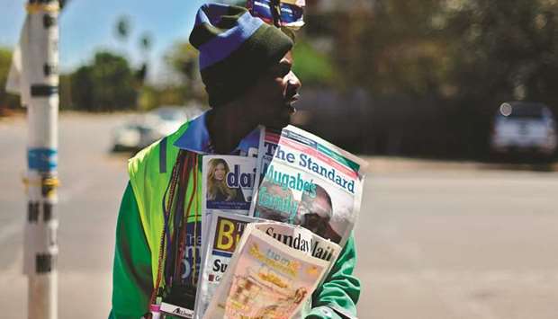 A street vendor sells newspapers in the streets of Harare, carrying a picture of late former president Robert Mugabe.