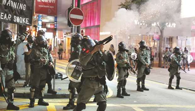 A riot police officer fires tear gas against protesters in Hong Kong.