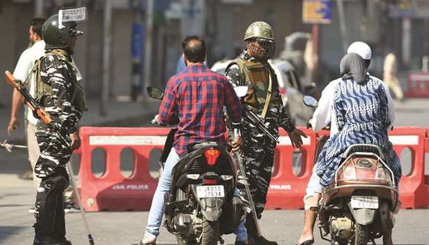 Paramilitary troopers stop motorcyclists during a strict curfew in Lal Chowk area of Srinagar yesterday.