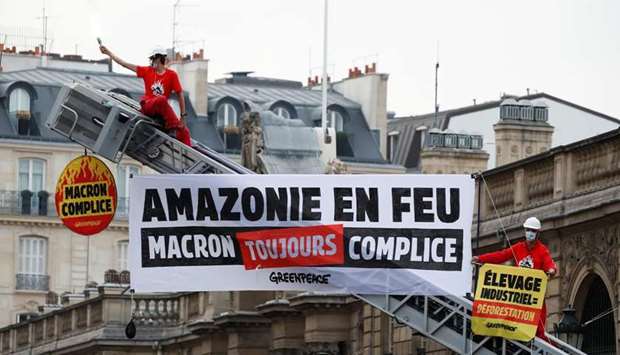 Greenpeace activists stand on a fire truck during an action in front of the Elysee Palace to protest