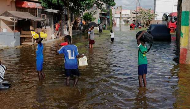 Residents make their way through a flood street after last week's heavy rains in Keur Massar, Senegal
