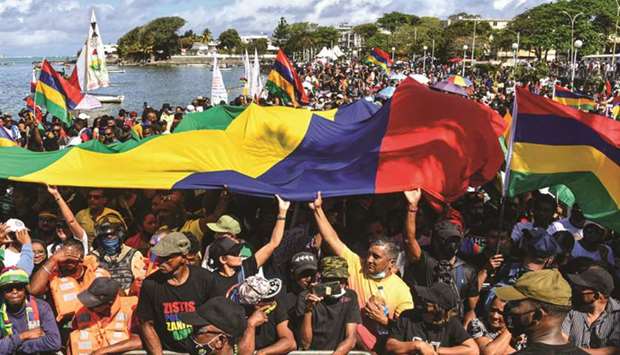 Protesters wave a giant Mauritiusu2019 national flag as they take part in a demonstration calling for the government to resign over the oil spill, in Mahebourg yesterday.